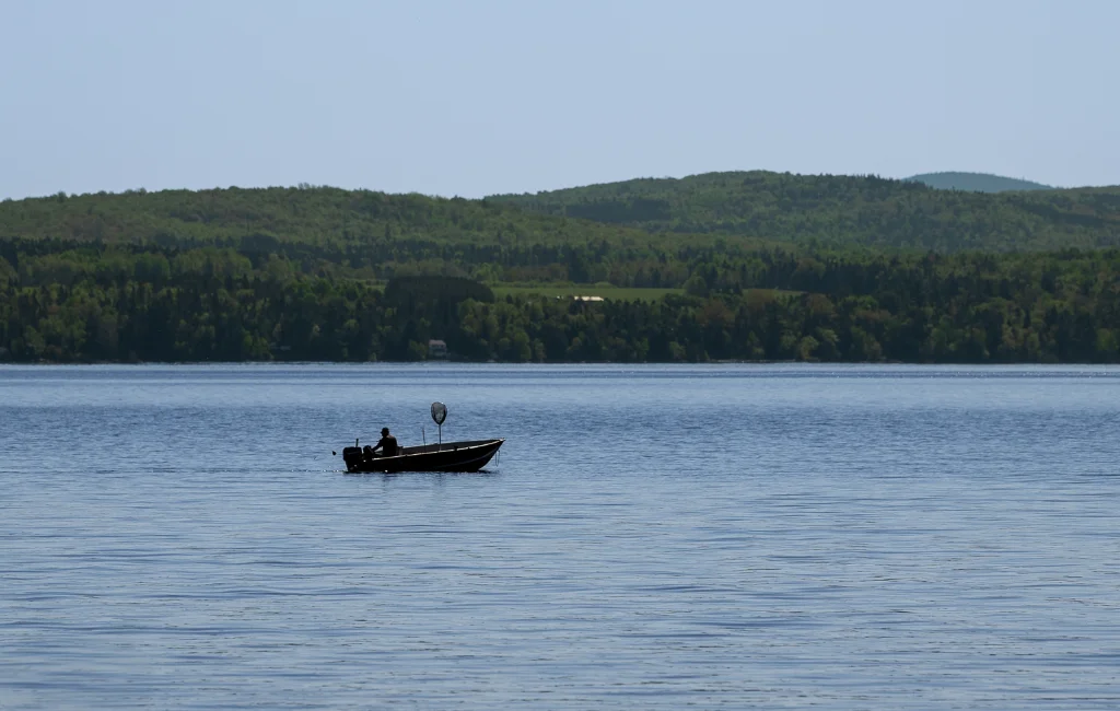 Pêcheur en chaloupe sur le lac Mégantic en été, collines des Appalaches