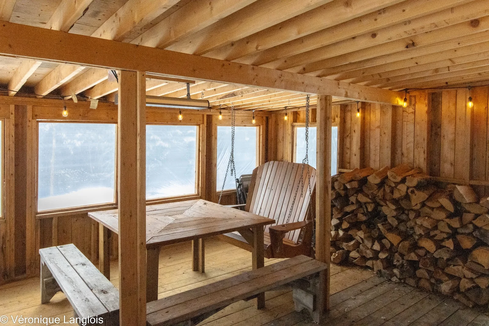 Véranda avec table, chaise Adirondack et réserve de bois