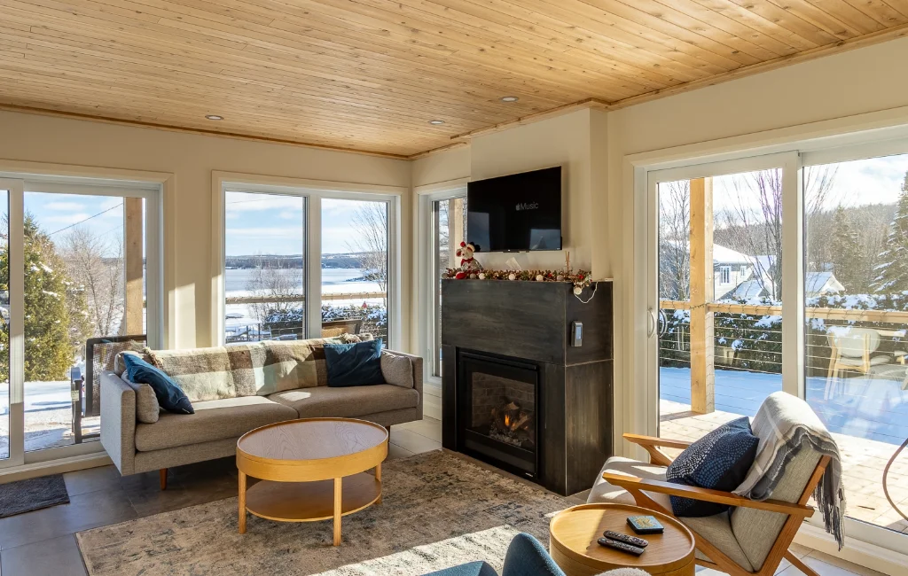 Salon avec foyer et grandes fenêtres donnant sur le lac en hiver