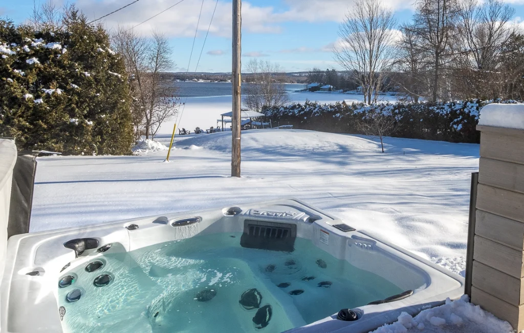 Spa extérieur dans la neige avec vue sur le lac gelé
